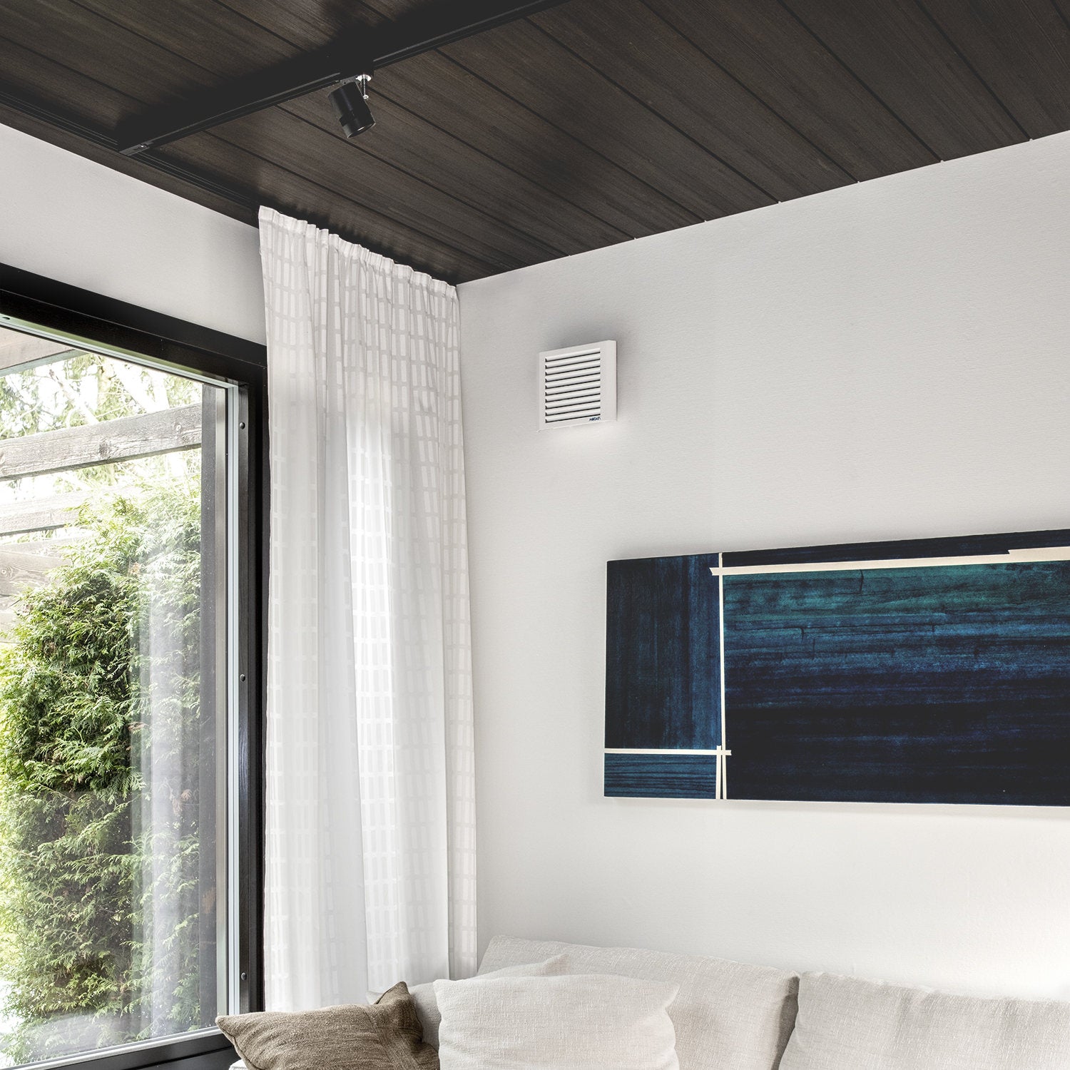 Room interior with a window, Mobair S fresh air valve mounted on a wall, and a light fixture.